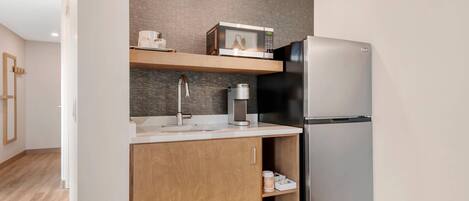 Una cocina moderna con un refrigerador de acero inoxidable, un microondas y una cafetera sobre una encimera de madera.