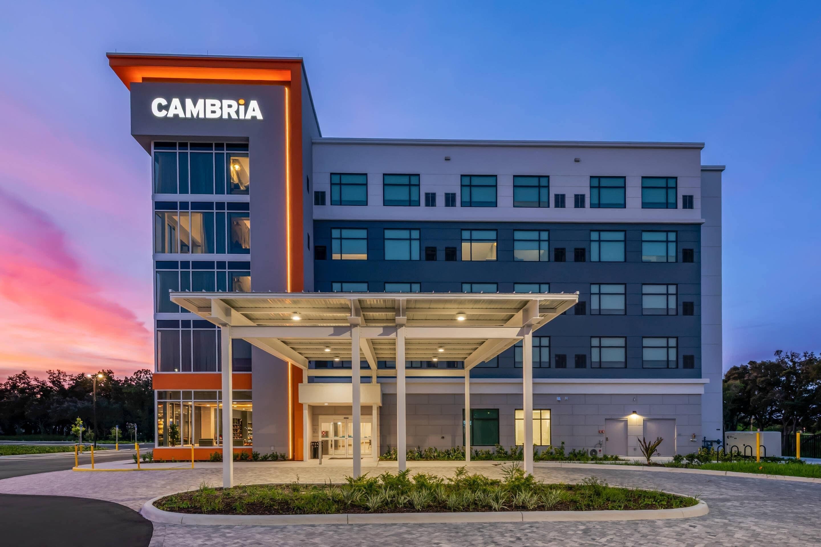 A modern building with a 'CAMBRIA' sign, featuring a covered entrance area and multiple windows.