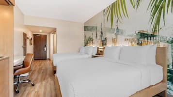 A hotel room with two beds, a desk, and a chair.