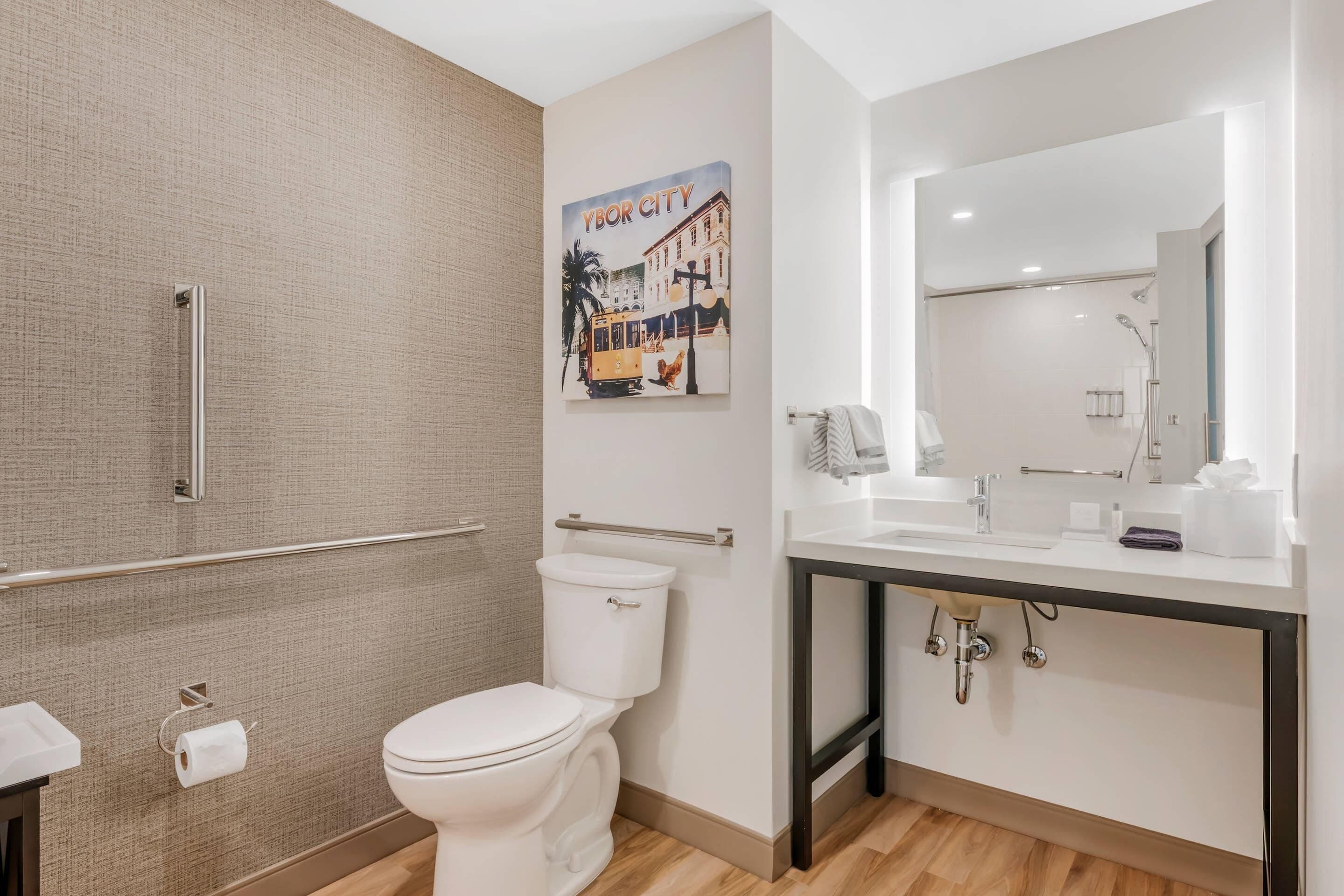 A modern bathroom with a toilet, a shower area, and a sink with a mirror.