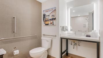 A modern bathroom with a toilet, a shower area, and a sink with a mirror.