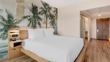 A modern hotel room with a large bed, a nightstand, a wall mural, and a wooden floor.