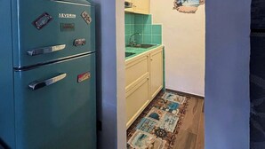 A compact kitchen with a teal refrigerator, a small sink, and a tiled backsplash.