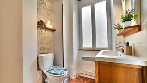 A bathroom with a white toilet, a window, a sink, and a wooden cabinet. - ღ Jungle Rochelaise • Hypercentre, 4K TV, Fibre (La Rochelle)