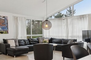A modern living room with a sectional sofa, a round coffee table, and a hanging light fixture.