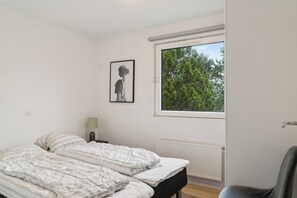 Una camera da letto con un letto, una finestra, un termosifone e un quadro appeso al muro.