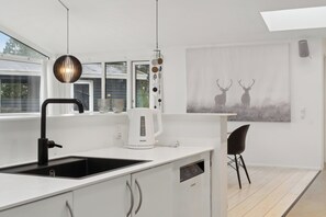 A modern kitchen with a sink, a coffee maker, and a chair.