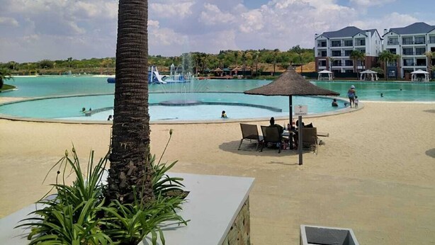 Un resort con piscina, zona de descanso y una palmera.