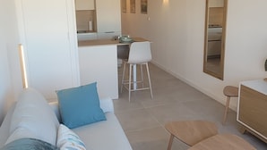 A modern living room with a sofa, a coffee table, and a dining area. - Cosy apartment large T1 of 32m2, direct access to the beach (Mauguio)