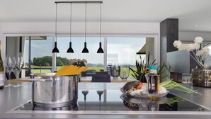 A modern kitchen with a large island, stainless steel appliances, hanging pendant lights, and a view of the outdoors. - Apartment 'Riedheide, 130qm' with Private Terrace, Private Garden and Wi-Fi (Bad Wurzach)