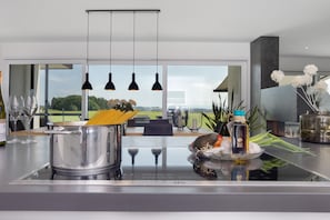 A modern kitchen with a large island, stainless steel appliances, hanging pendant lights, and a view of the outdoors. - Apartment 'Riedheide, 130qm' with Private Terrace, Private Garden and Wi-Fi (Bad Wurzach)