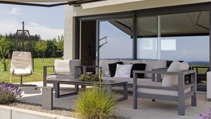 An outdoor seating area with a sofa, chairs, and a table, overlooking a scenic landscape. - Apartment 'Riedheide, 130qm' with Private Terrace, Private Garden and Wi-Fi (Bad Wurzach)