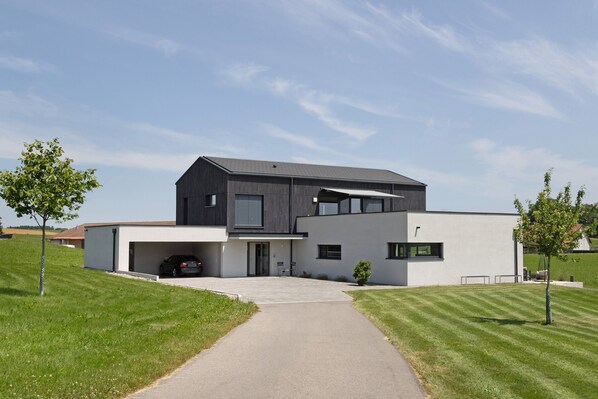 A modern two-story house with a garage, a paved driveway, and a well-maintained lawn.