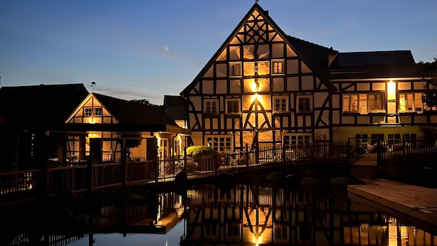A traditional half-timbered building with a reflection in the water, a clear sky, and a calm evening setting. - Apartment 'Kornkammer' with Shared Garden, Balcony and Wi-Fi (Finnentrop)