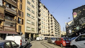 A multi-story residential building with balconies, parked cars, and a large billboard. - GuestHost - Naviglio Pavese Comfortable Apt with Balcony! (Milano)