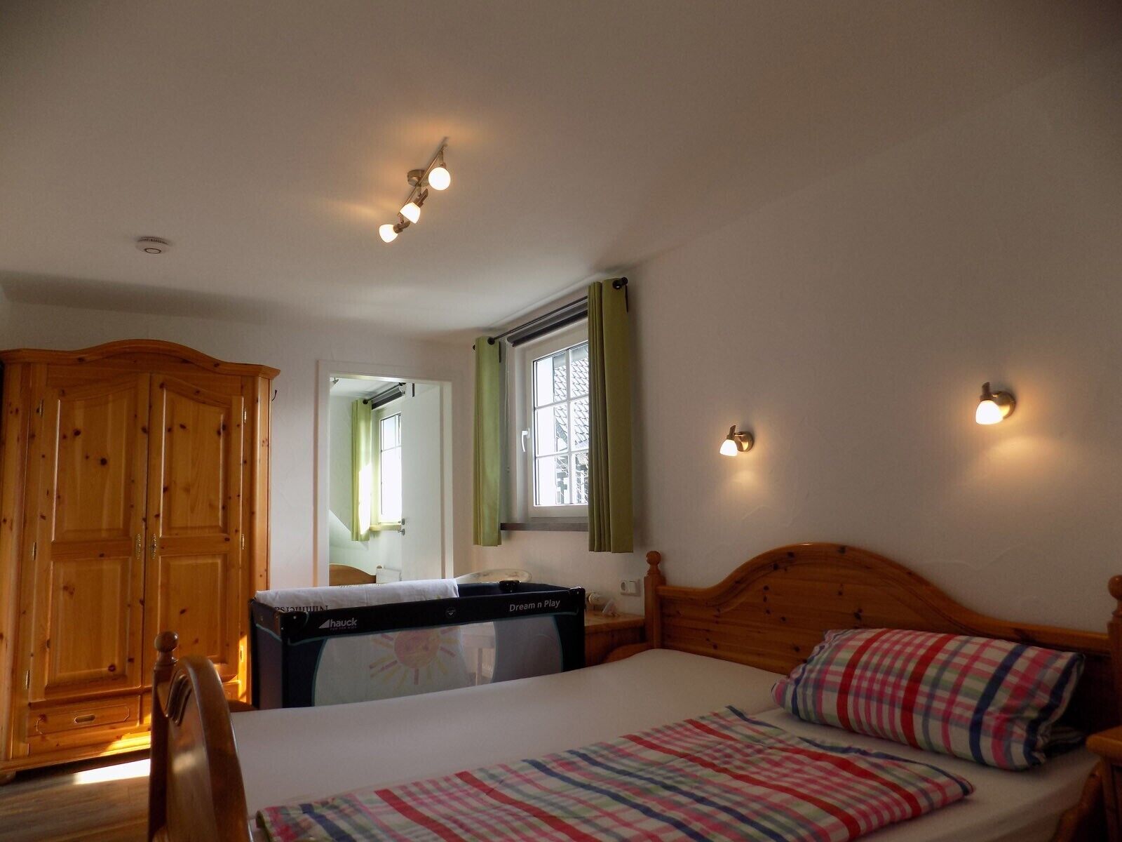 Ein Schlafzimmer mit einem Bett, einem Holzschrank, einem Fernseher und einem Fenster mit Vorhängen.
