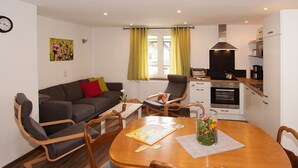 Un espace de vie compact comprenant un coin repas, une kitchenette et un espace détente.