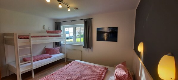A bunk bed room with a window, a painting, and a lamp.