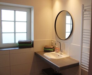 A bathroom with a window, a sink, a mirror, and a towel rack.