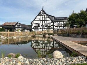 A traditional half-timbered building with a pond and wooden deck. - Apartment 'Apfelbaum' with Private Terrace, Shared Garden and Wi-Fi (Finnentrop)