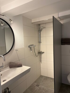 A bathroom with a sink, mirror, shower, and towel. - Apartment 'Apfelbaum' with Private Terrace, Shared Garden and Wi-Fi (Finnentrop)