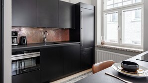 A modern kitchen with dark cabinetry, a built-in oven, and a window providing natural light.