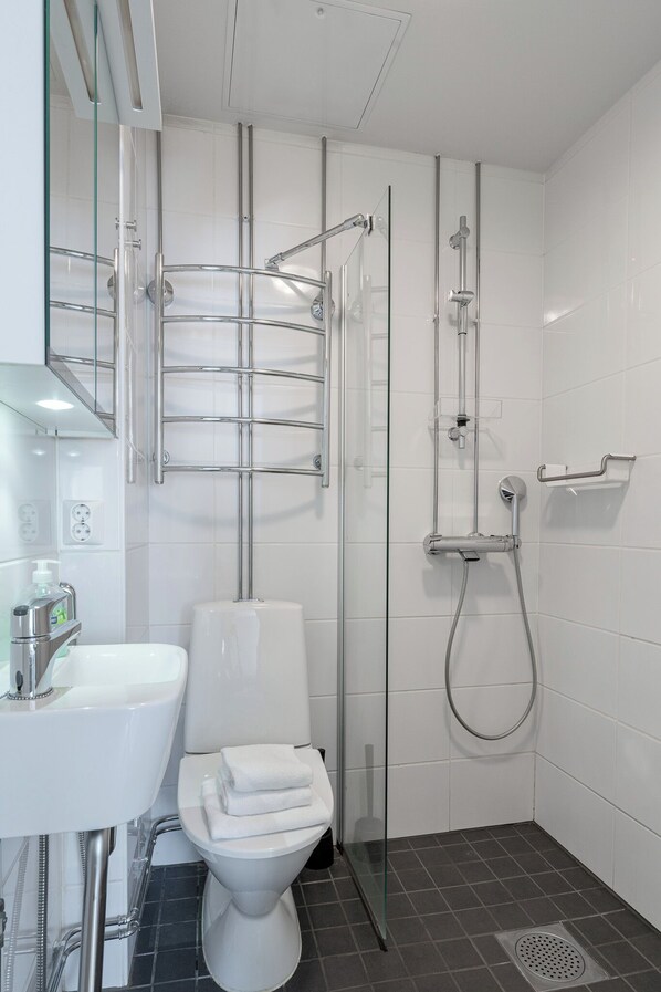 A modern bathroom with a glass-enclosed shower, a white sink, and a toilet. - Historical Studio & Excellent Location (Tampere)