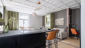 A modern kitchen with a central island, a dining area with a sofa and chairs, and a living area with a couch and a coffee table. - Historical Studio & Excellent Location (Tampere)