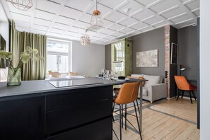 A modern kitchen with a central island, a dining area with a sofa and chairs, and a living area with a couch and a coffee table. - Historical Studio & Excellent Location (Tampere)
