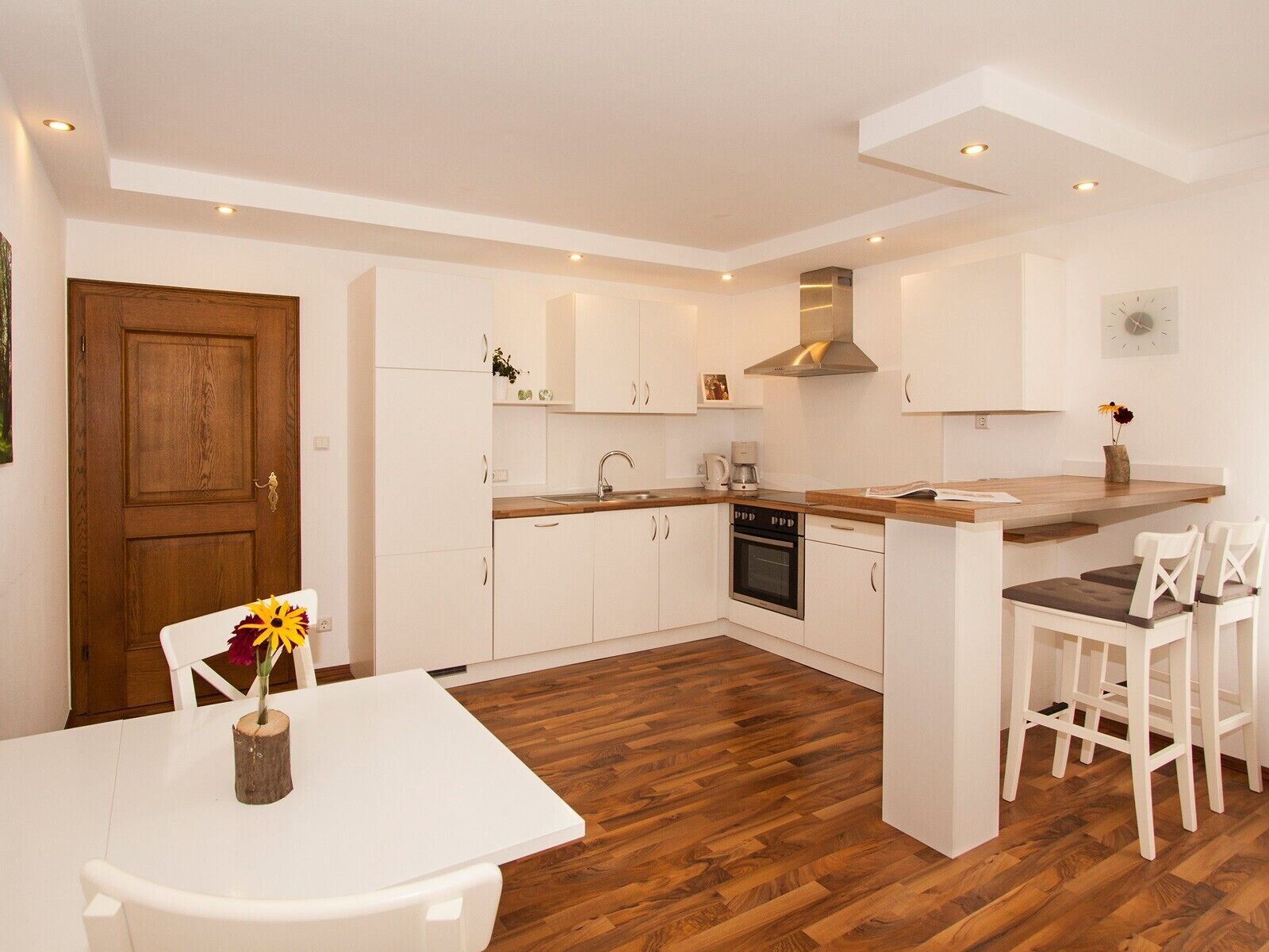Eine moderne Küche mit weißen Schränken, einer Holz Arbeitsplatte und einem eingebauten Backofen.
