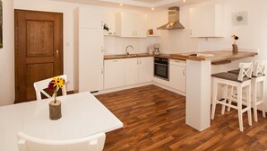 A modern kitchen with white cabinets, a wooden countertop, and a built-in oven. - Apartment 'Sonnenblume' with Private Terrace, Shared Garden and Wi-Fi (Finnentrop)