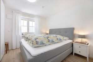 Une chambre à coucher avec un lit, une table de chevet et une fenêtre avec des rideaux.
