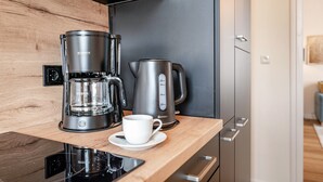 A modern kitchen with a coffee maker, a kettle, and a cup on a wooden countertop. - Holiday Apartment 'Seestern' with Shared Garden and Wi-Fi (Kühlungsborn)