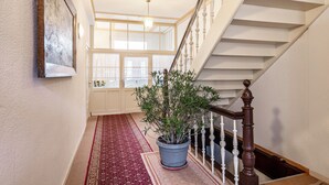 A staircase with white balusters and a red carpet leading to a room with a large window and a potted plant. - Holiday Apartment 'Seestern' with Shared Garden and Wi-Fi (Kühlungsborn)