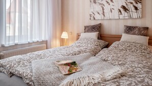 A bedroom with two beds, a window with sheer curtains, a bedside lamp, and a wall-mounted artwork. - Holiday Apartment 'Seestern' with Shared Garden and Wi-Fi (Kühlungsborn)