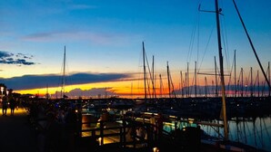 A marina at sunset with boats docked, a pedestrian walkway, and a bridge in the background. - Holiday Apartment 'Seestern' with Shared Garden and Wi-Fi (Kühlungsborn)