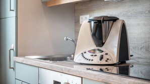 Une cuisine équipée d’un appareil à café moderne posé sur le plan de travail, d’un évier et de meubles de couleur claire.