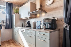 Eine moderne Küche mit eingebautem Geschirrspüler, einer Kaffeemaschine und einer Wanduhr.