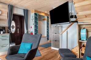 Ein Zimmer mit Fernseher, zwei Stühlen, Holzboden und einem Kleiderschrank mit Schubladen.