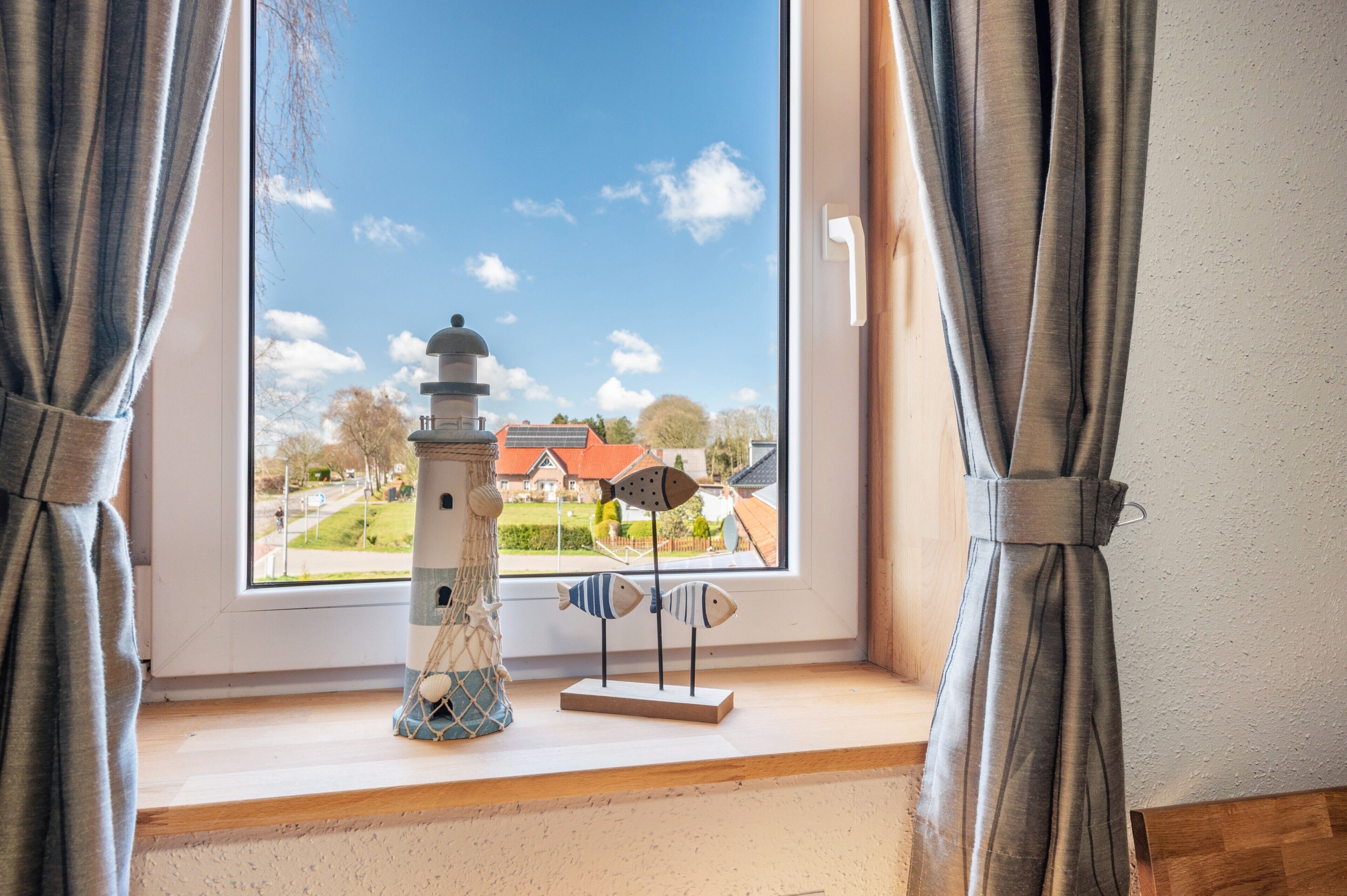 Een uitzicht op een huis en een miniatuurvuurtoren vanuit een raam.