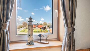 Een uitzicht op een huis en een miniatuurvuurtoren vanuit een raam.
