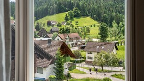 A view of a village with traditional houses, a green hill, and a forested area. - Apartment 'Klassenzimmer' with Mountain View, Shared Terrace and Wi-Fi (Enzklösterle)
