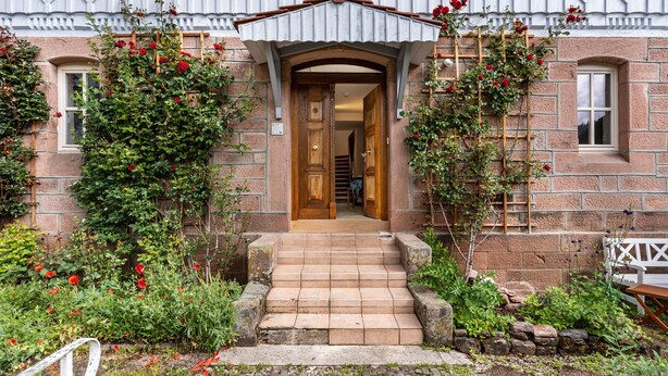 A stone building with a wooden door, steps leading to the entrance, and a white fence. - Apartment 'Klassenzimmer' with Mountain View, Shared Terrace and Wi-Fi (Enzklösterle)