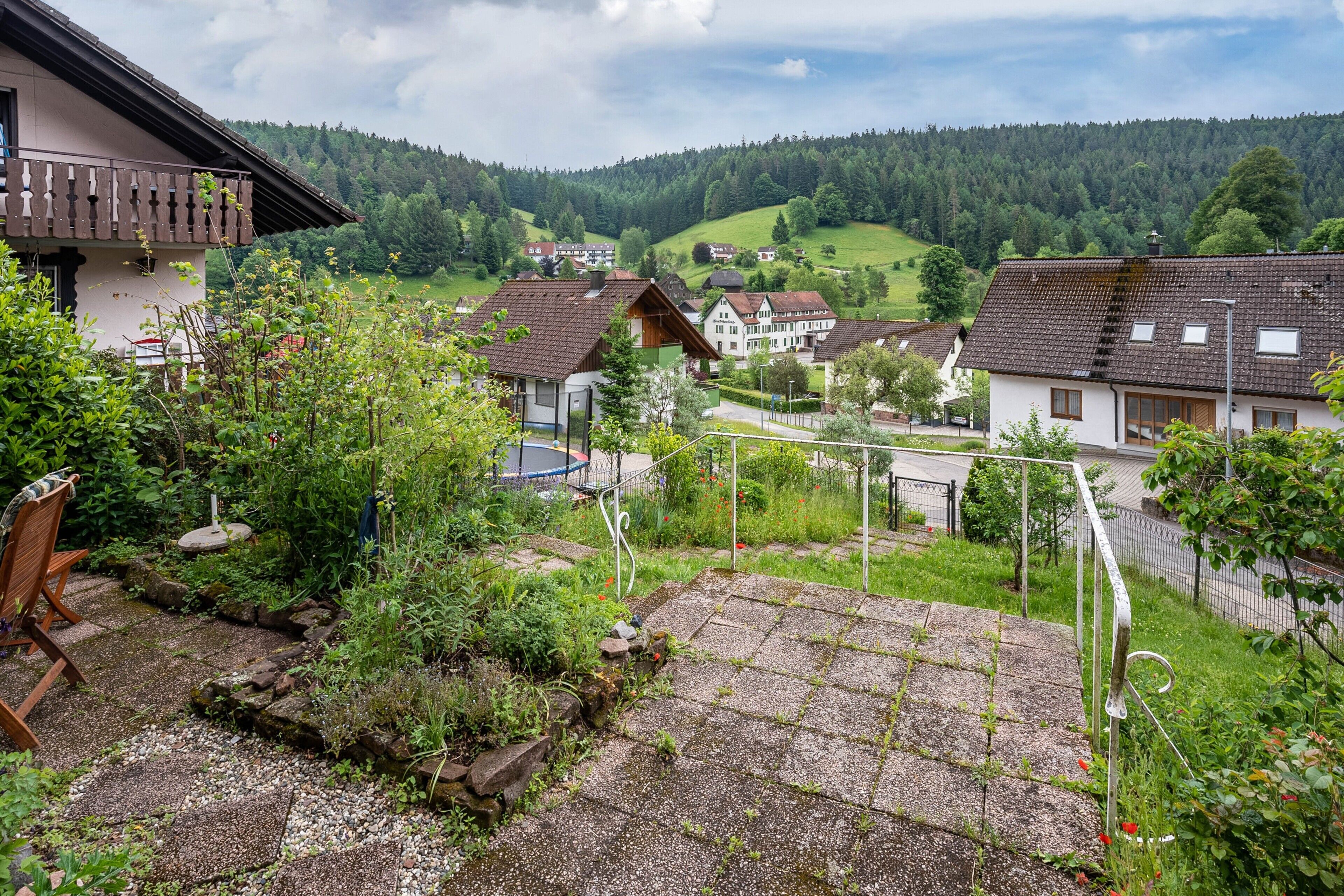 Un quartier résidentiel avec des maisons, un jardin et une vue sur une colline boisée.