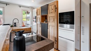 A modern kitchen with a wooden cabinet, a black kettle, and a built-in stove.