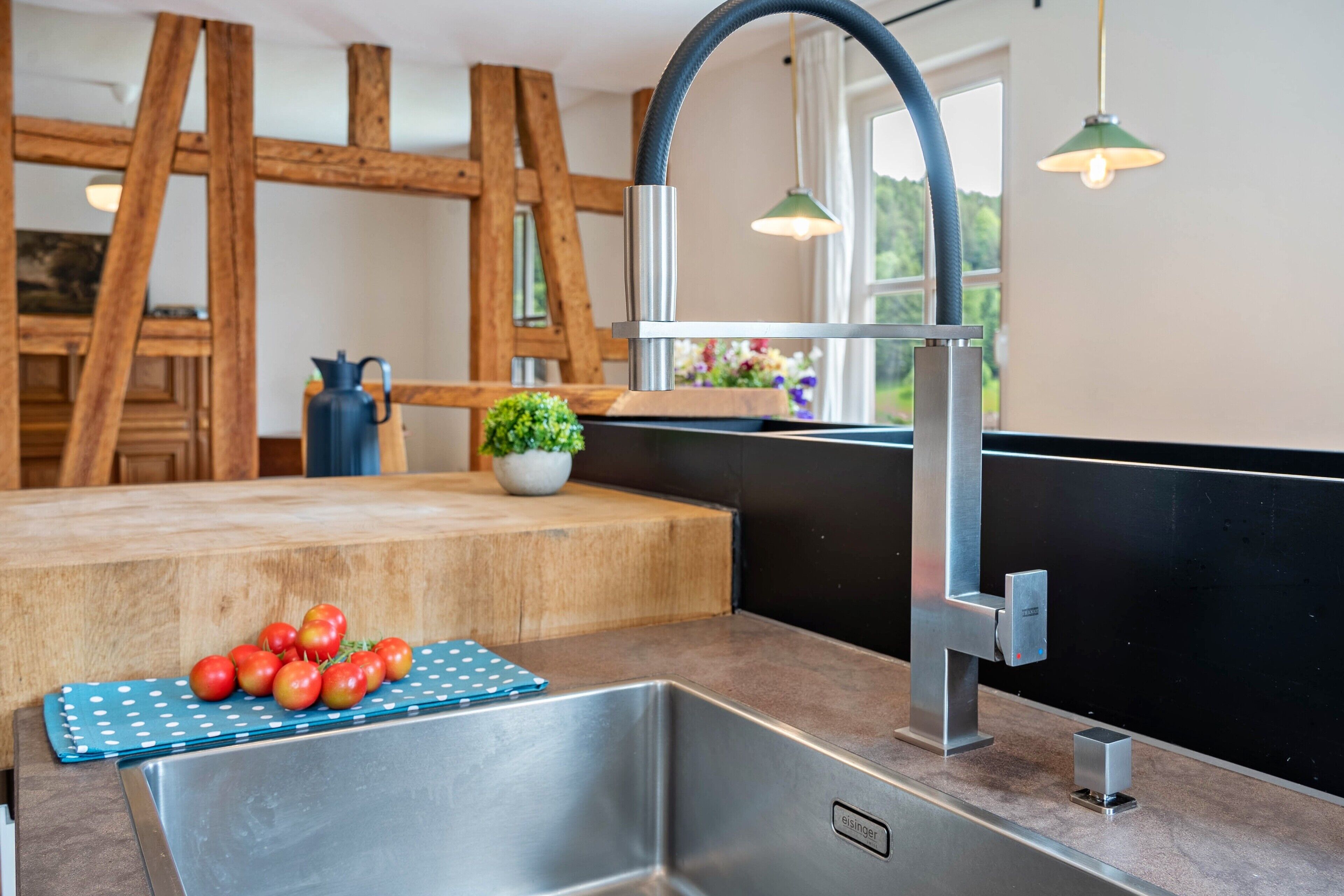 Una cocina moderna con pileta de acero inoxidable, detalles de madera y vista al exterior.