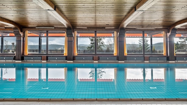 Une piscine avec des poutres en bois et de grandes fenêtres.