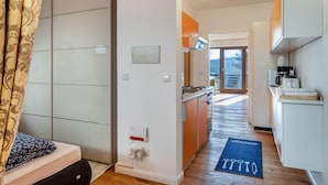 Une chambre d’hôtel moderne équipée d’un lit, d’une armoire, d’une kitchenette et offrant une vue sur l’extérieur.