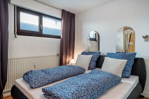 Une chambre à coucher avec un lit, une fenêtre, un miroir et un radiateur.