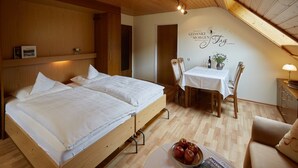 Une chambre avec deux lits, une table à manger avec des chaises et un mur orné d’un panneau décoratif.